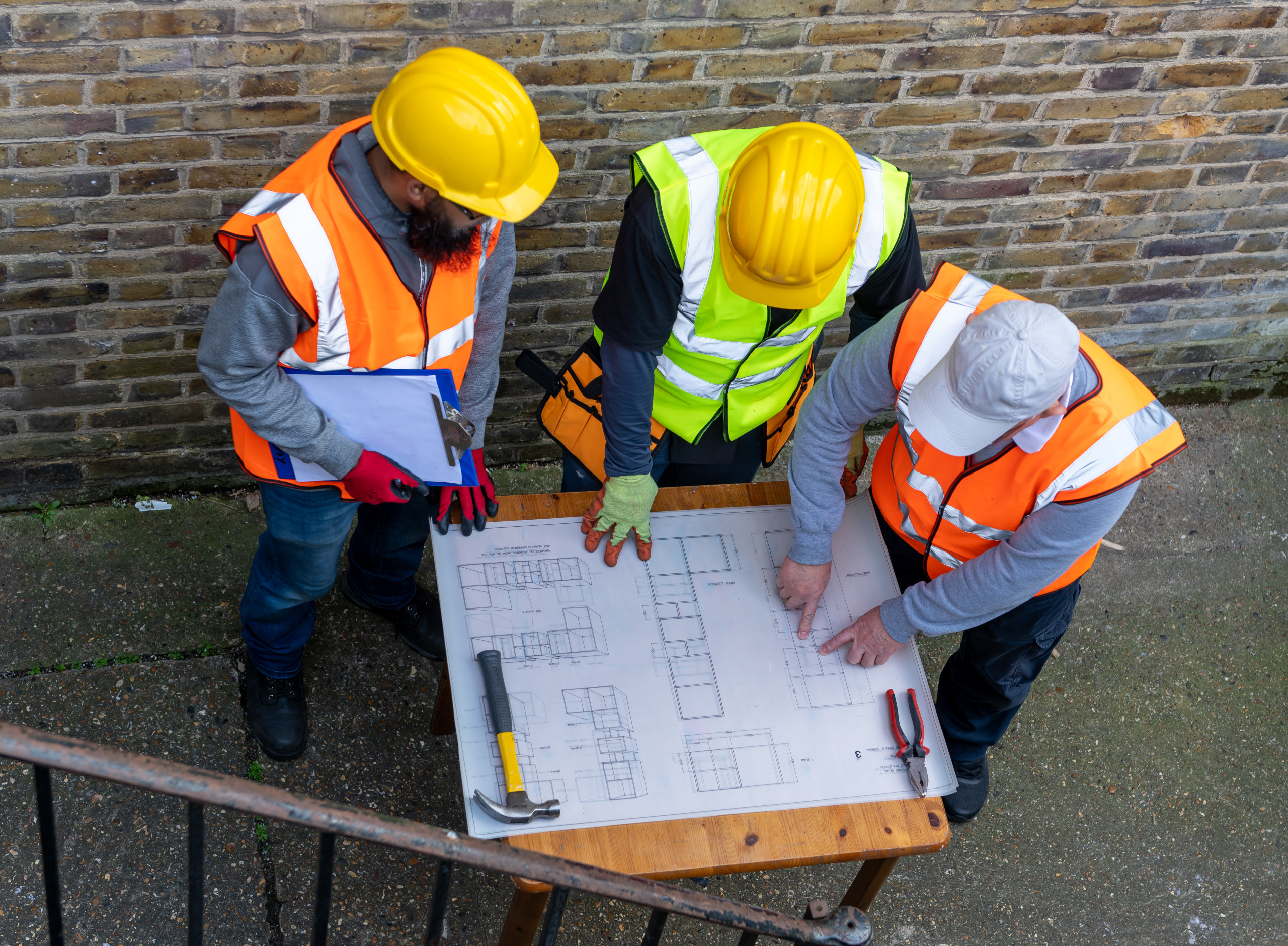 The architect with the building plan in discussion with the construction supervisors.